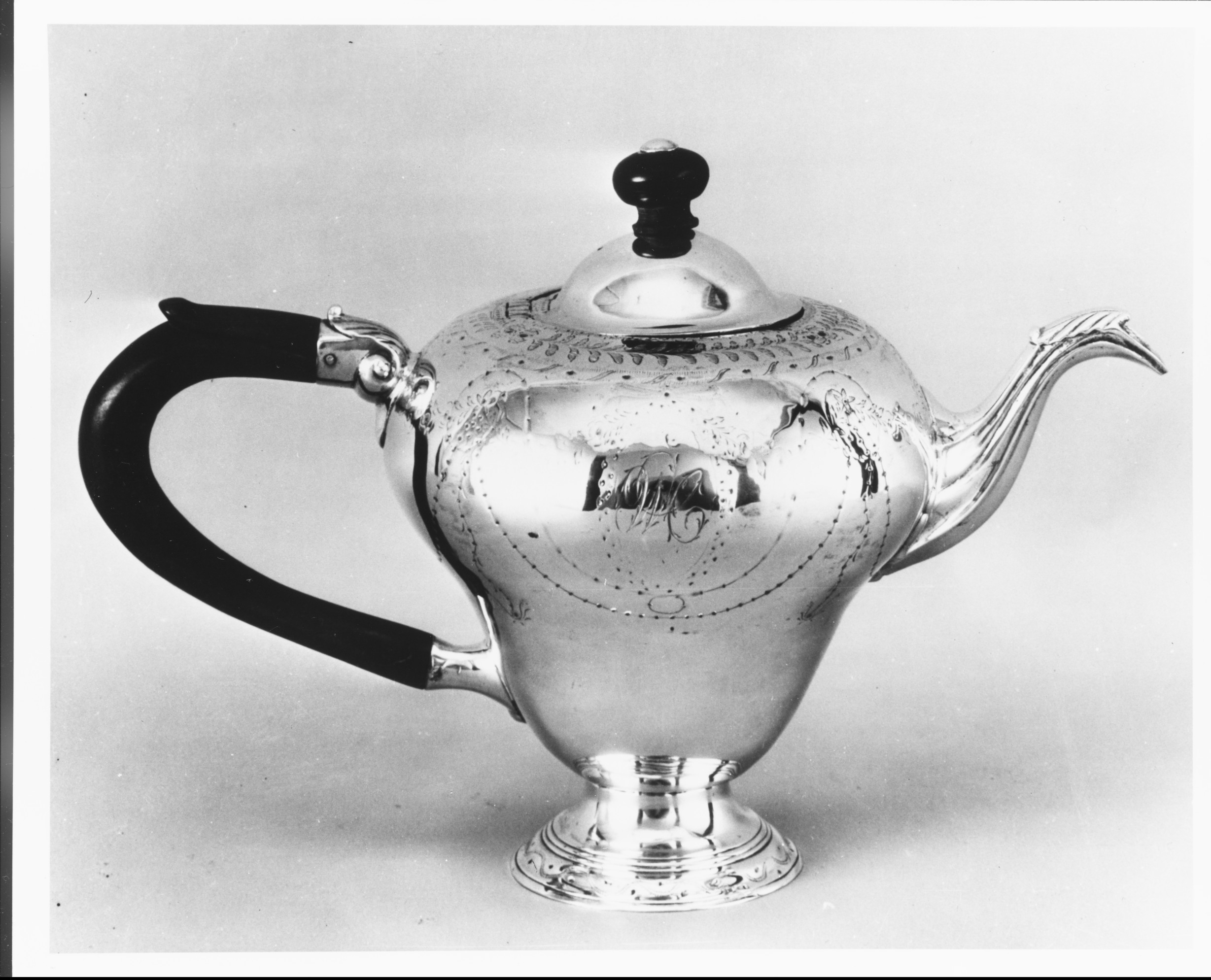 Close-up of the bottom of the silver teapot, showing surface wear, foot structure, and stamped marks